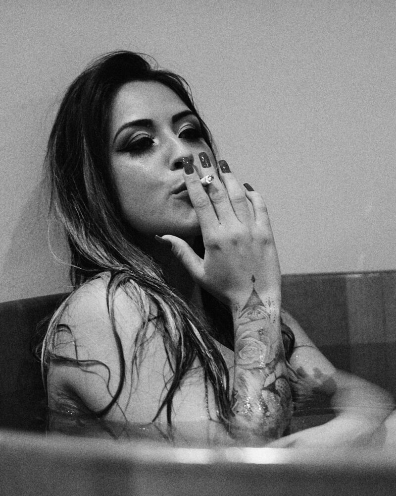 Preto e branco. Mulher posando para ensaio boudoir fumando em uma banheira