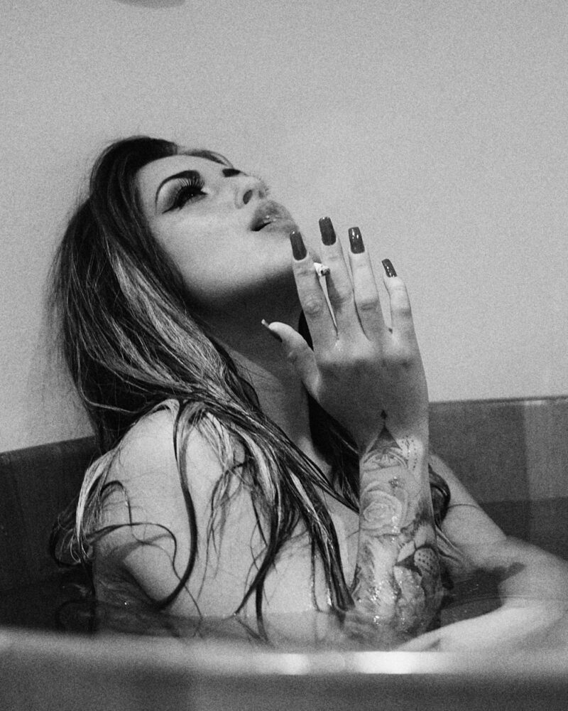 Preto e branco. Mulher posando para ensaio boudoir fumando em uma banheira