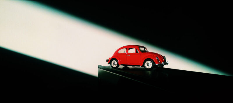 Miniatura de Fusca vermelho iluminado por um facho de luz em um ambiente escuro