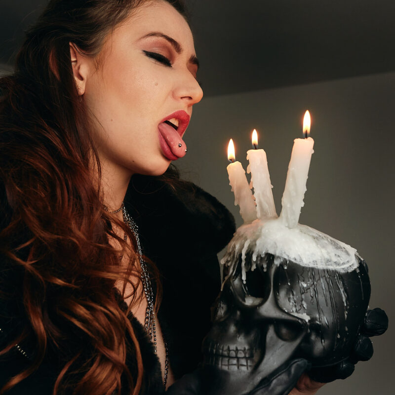 Mulher mostrando a língua segurando uma caveira com velas