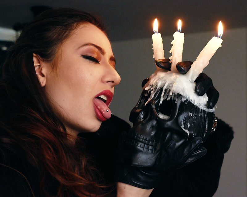 Mulher mostrando a língua segurando uma caveira com velas