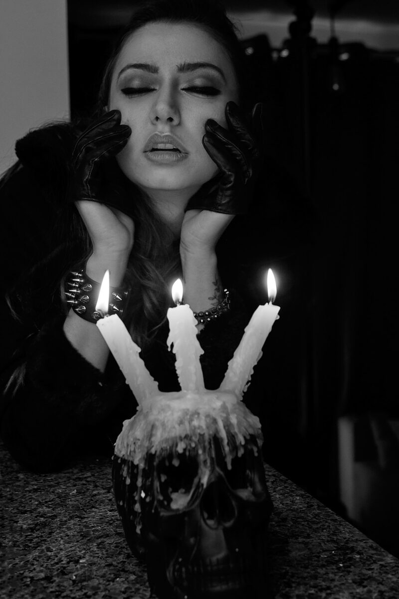 Preto e branco, mulher debruçada atrás de uma caveira com velas acesas