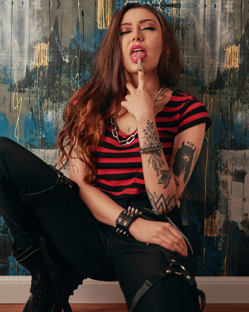 Mulher em frente a uma parede, posando para ensaio feminino, com um dedo na boca