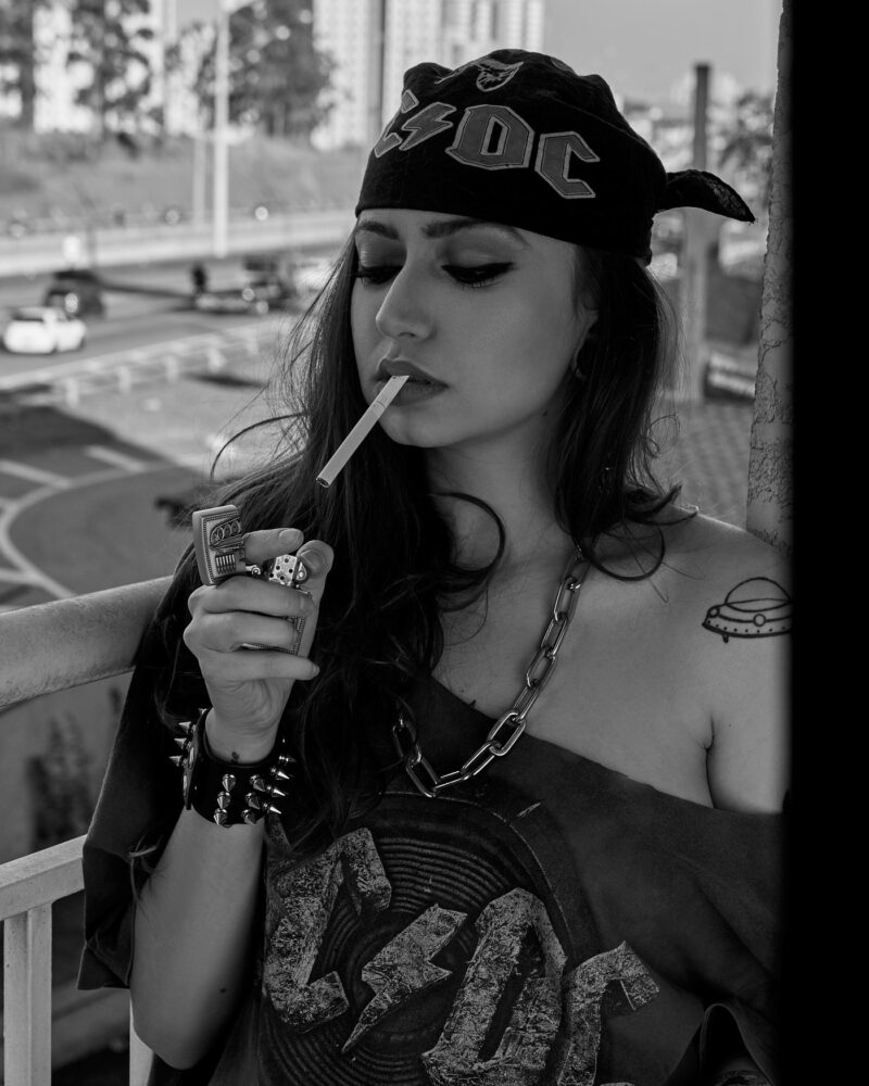 Mulher acendendo cigarro com uma rodovia ao fundo