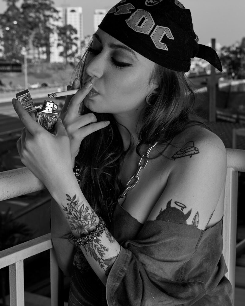 Mulher acendendo cigarro com uma rodovia ao fundo