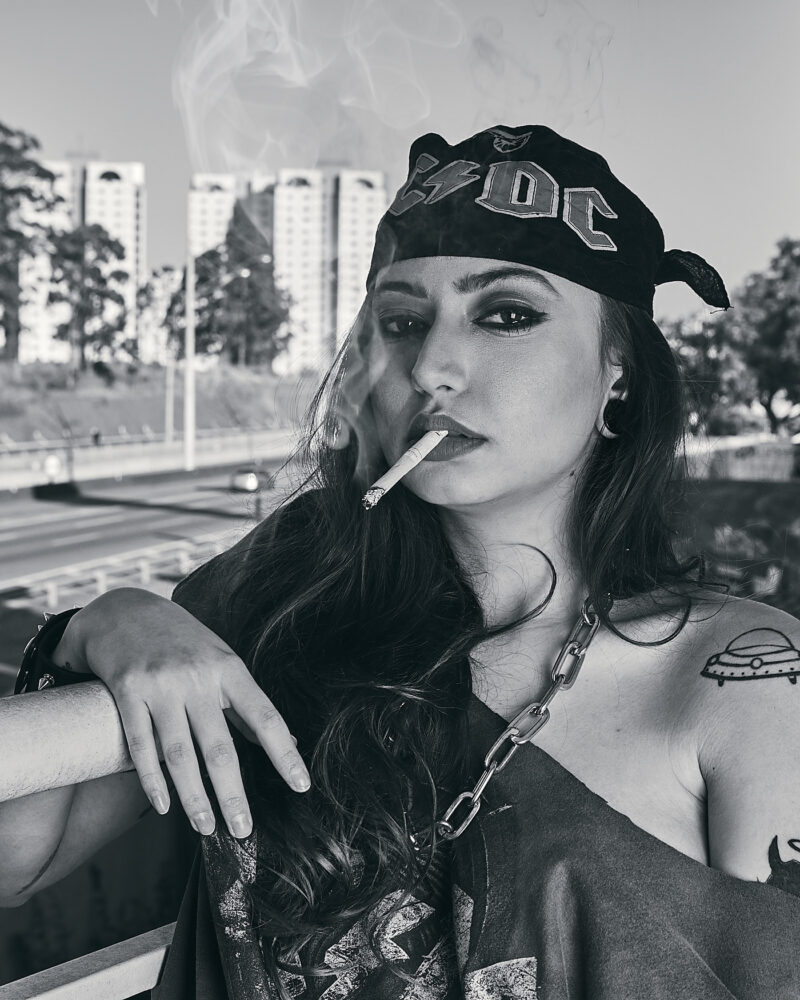 Mulher posando com cigarro aceso soltando fumaça