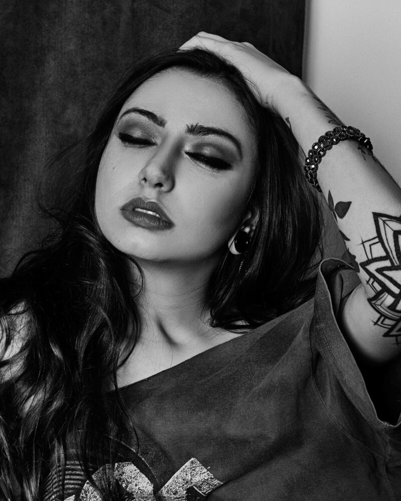 Mulher passando a mão no cabelo com os olhos fechados, foto em preto e branco