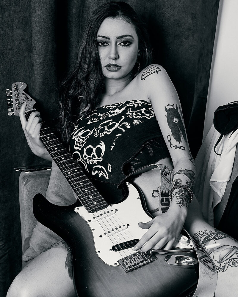Mulher posando com uma guitarra em cima do sofá