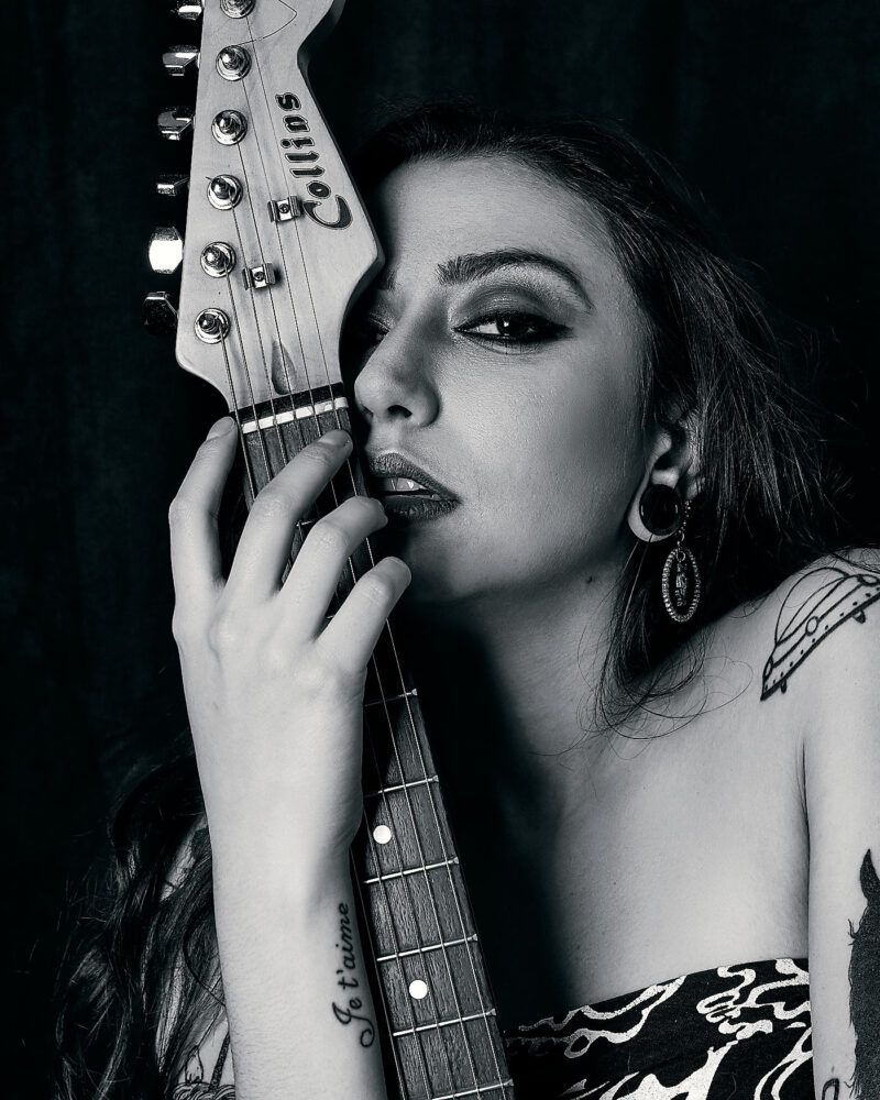 Mulher posando com uma guitarra próxima ao rosto
