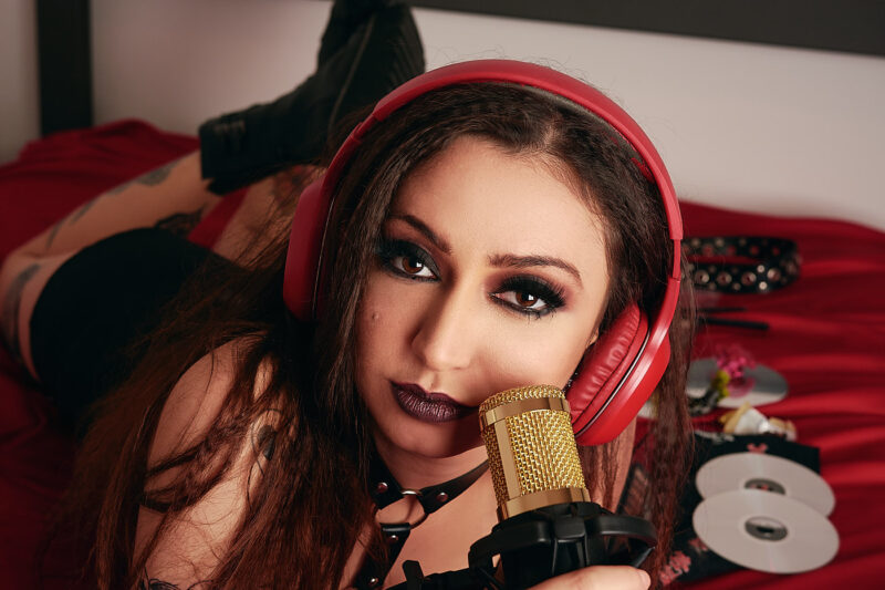 Retrato de mulher com um fone vermelho e um microfone dourado